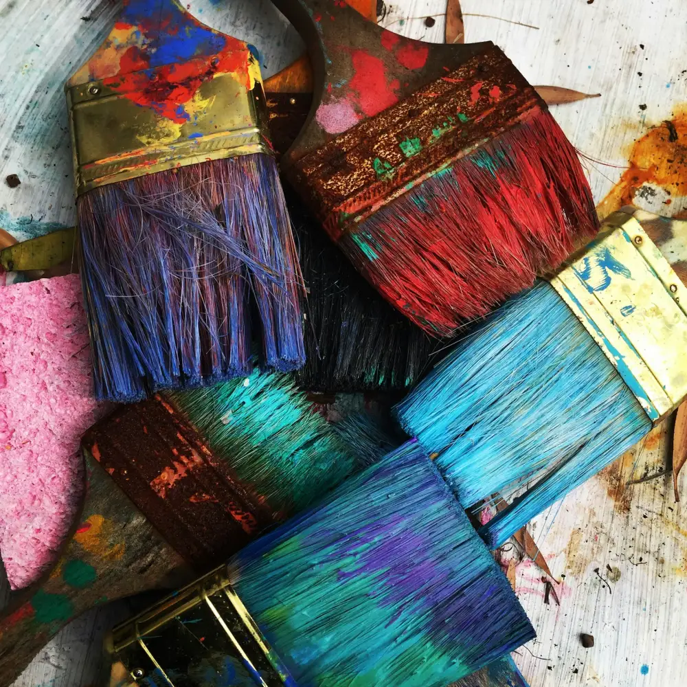 Paint-splattered brushes and a sponge on a studio table